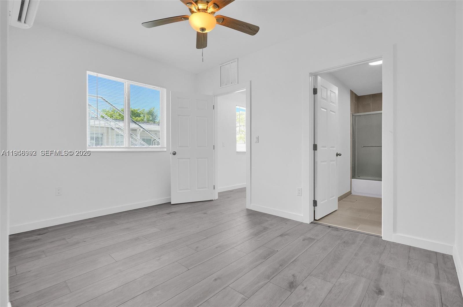 A bedroom features gray wood-look flooring, a ceiling fan, and an attached bathroom — 600 NW 25th Ct, Miami FL 33125, MIAMI, FL
