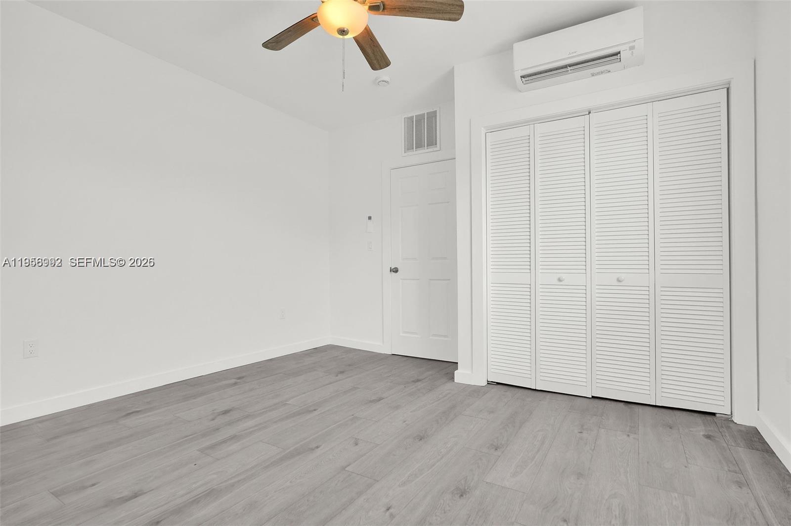 A bedroom features white walls, gray wood-look flooring, a ceiling fan, and a white closet — 600 NW 25th Ct, Miami FL 33125, MIAMI, FL