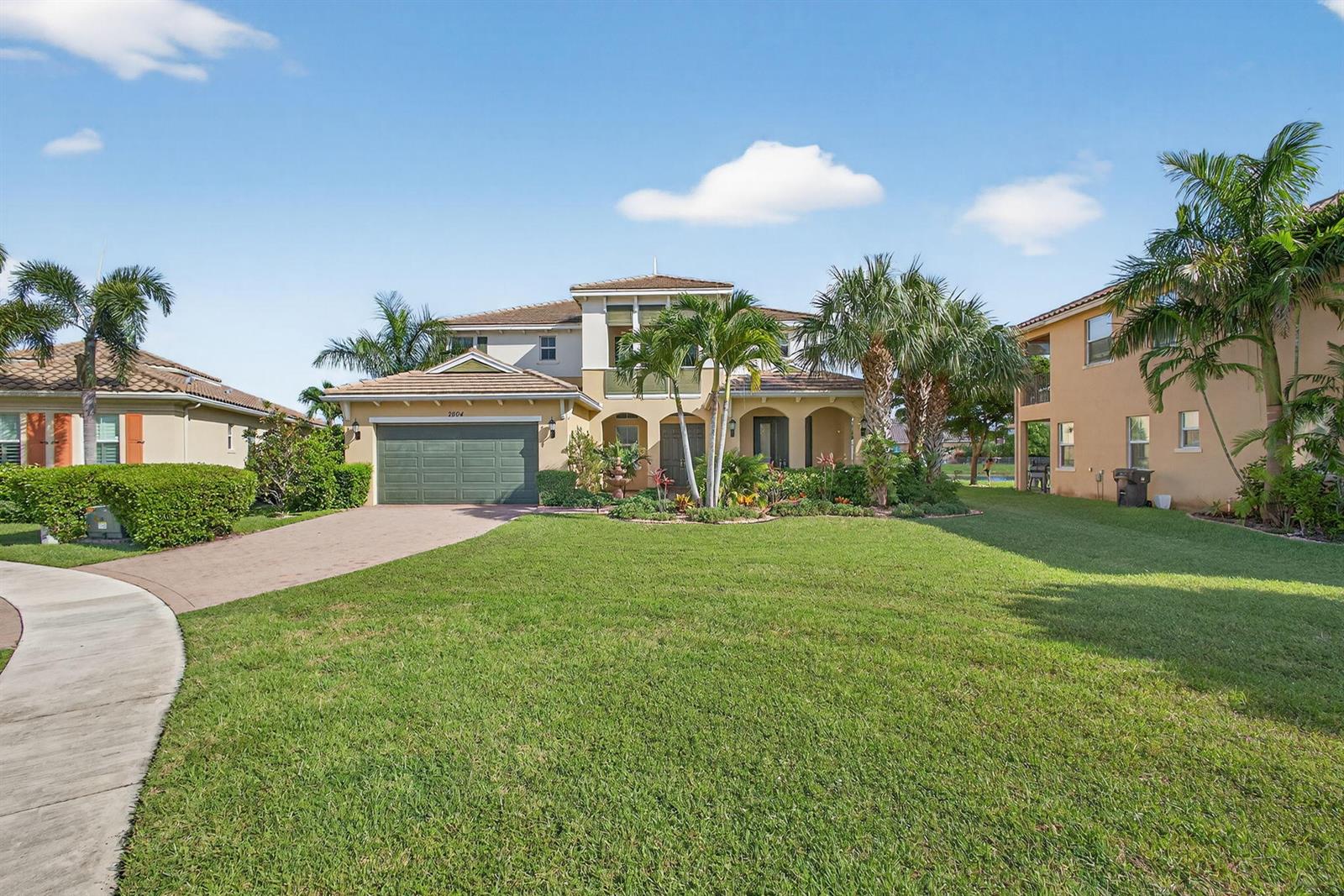 A two-story suburban house with a green garage door, palm trees, and a front lawn — 2904 Payson Way, Wellington FL 33414, WELLINGTON, FL