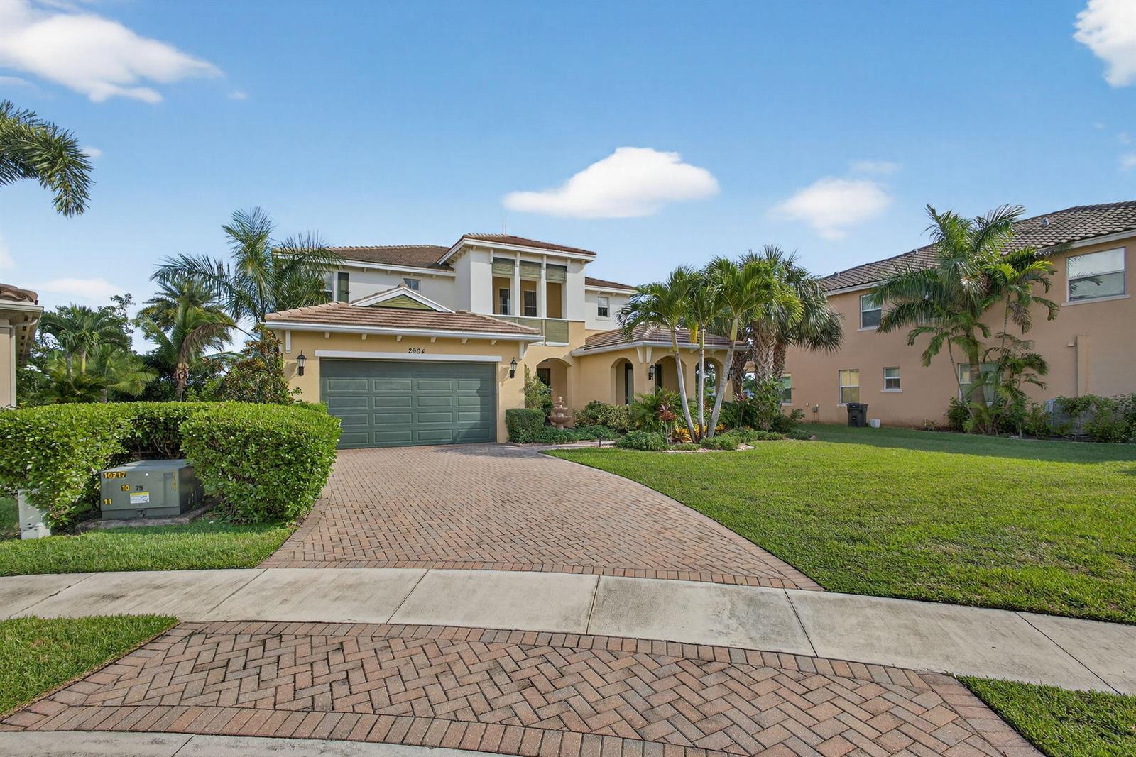 A two-story suburban house with a paved driveway, green garage door, and palm trees — 2904 Payson Way, Wellington FL 33414, WELLINGTON, FL