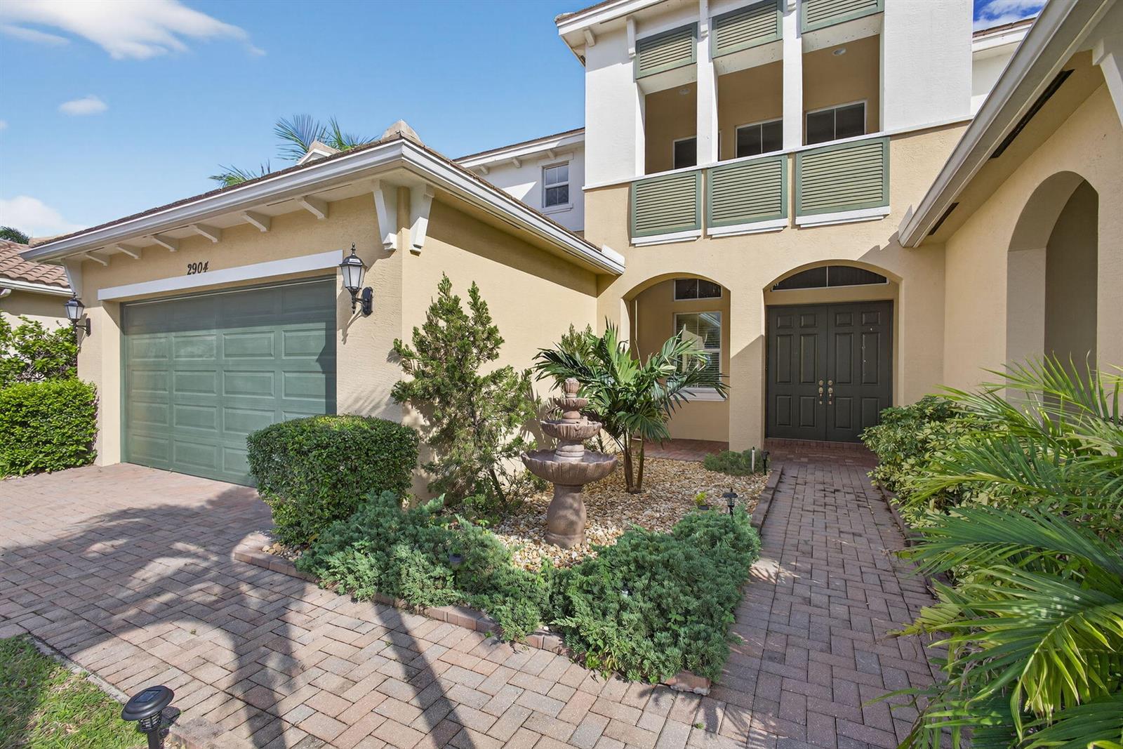 A two-story house with a green garage door, a stone fountain, and a brick walkway — 2904 Payson Way, Wellington FL 33414, WELLINGTON, FL