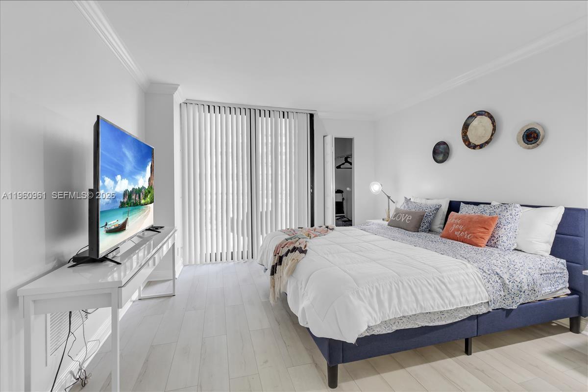 A bedroom features a blue upholstered bed, a white console table with a television, and vertical blinds — 3000 N Ocean Dr # 3B, Singer Island FL 33404, SINGER ISLAND, FL