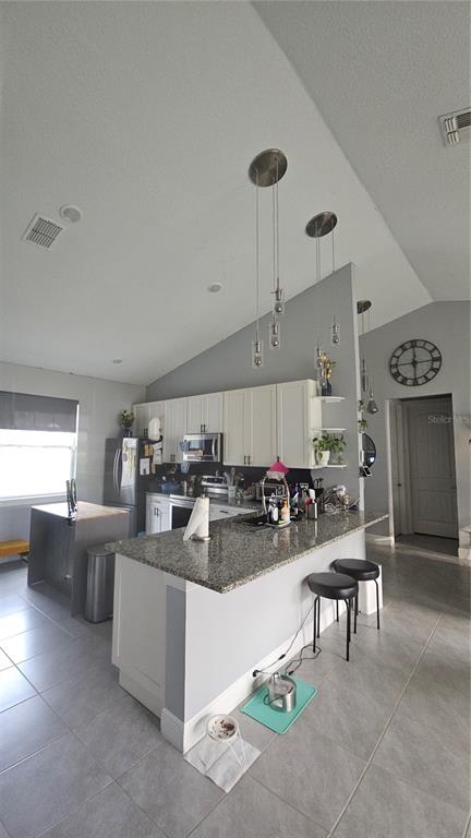 A kitchen features white cabinets, granite countertops, a breakfast bar, and pendant lighting — 1730 EAST PARKWAY, DELAND, FL