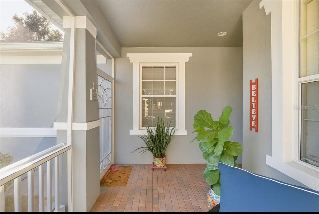 A covered front porch with a brick floor, a window, and two potted plants — 119 CRESCENT MOON DRIVE, GROVELAND, FL