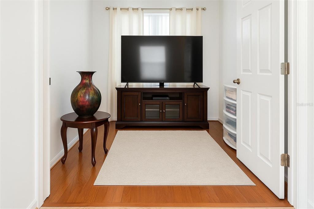 A room with hardwood floors, a television on a wooden stand, and a decorative vase — 119 CRESCENT MOON DRIVE, GROVELAND, FL