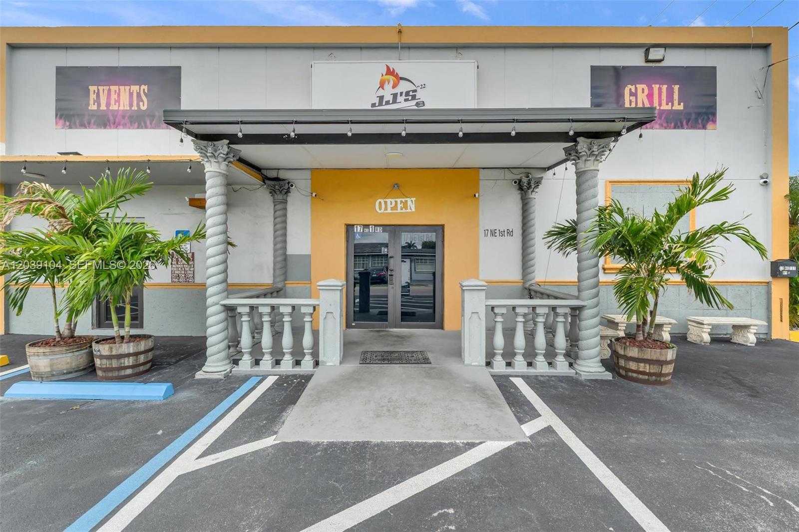 The exterior of a commercial building features a central entrance with columns and a railing — HOMESTEAD, FL