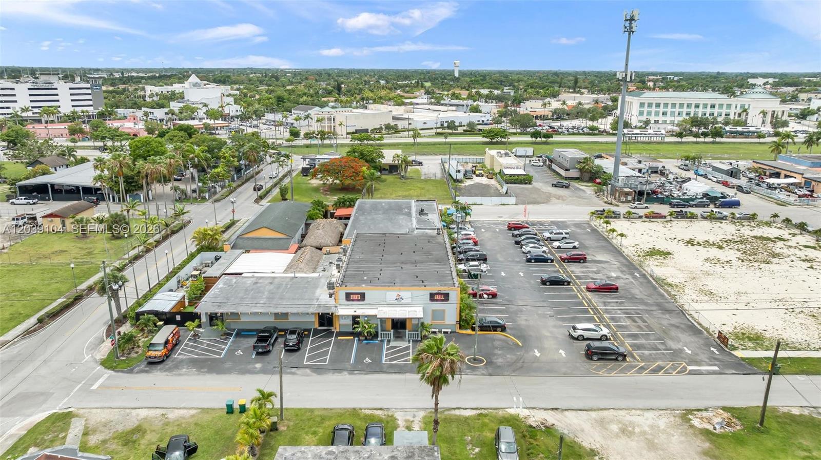 An aerial view shows a commercial building with a parking lot and surrounding landscape — HOMESTEAD, FL