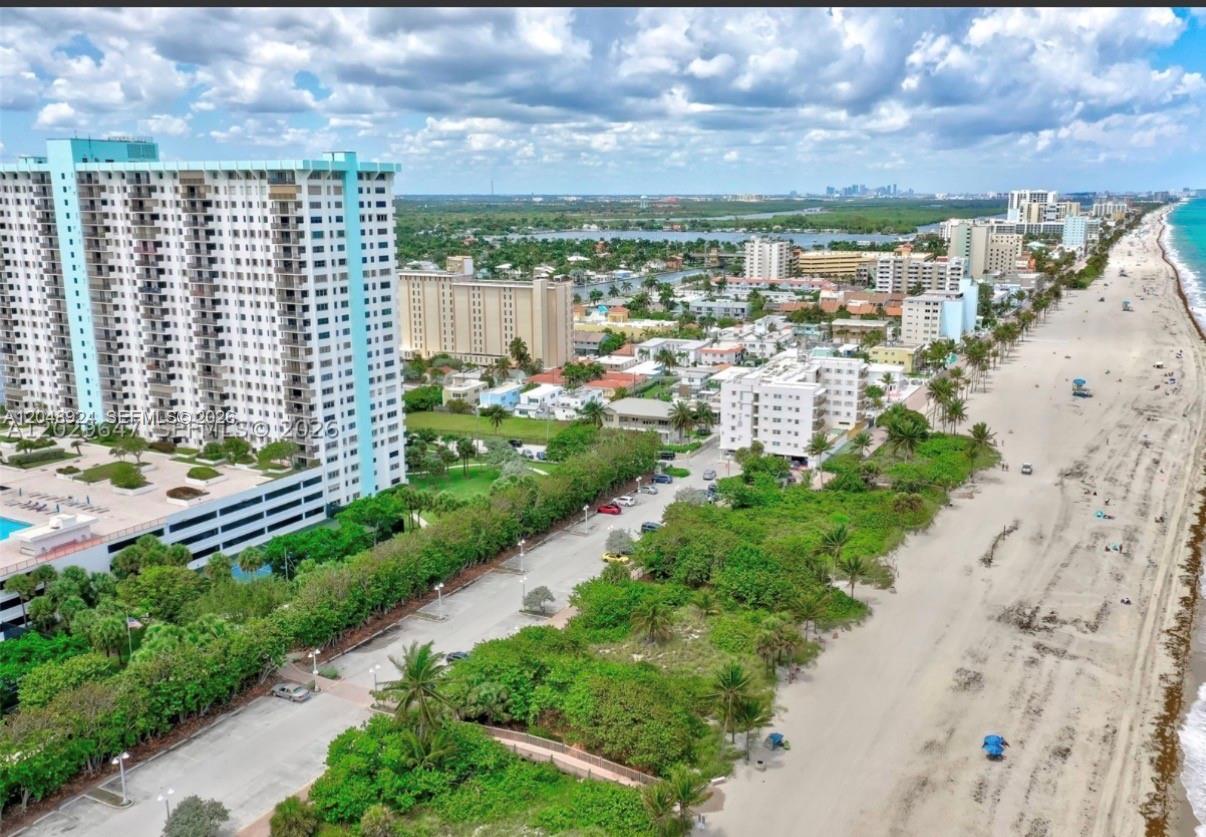 An aerial view shows a tall residential building next to a beach and coastal vegetation — 1201 S Ocean Dr # 410S, Hollywood FL 33019, HOLLYWOOD, FL