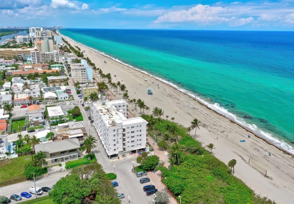 An aerial view shows a white multi-story apartment building situated beside a sandy beach — 1201 S Ocean Dr # 410S, Hollywood FL 33019, HOLLYWOOD, FL