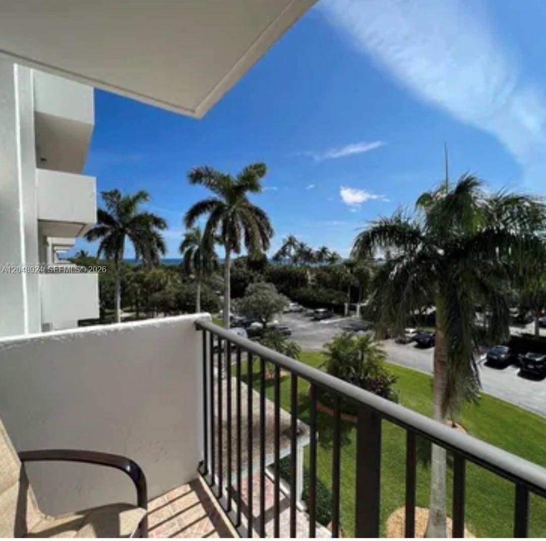 A balcony with a metal railing overlooks a parking lot, palm trees, and the ocean — 1201 S Ocean Dr # 410S, Hollywood FL 33019, HOLLYWOOD, FL