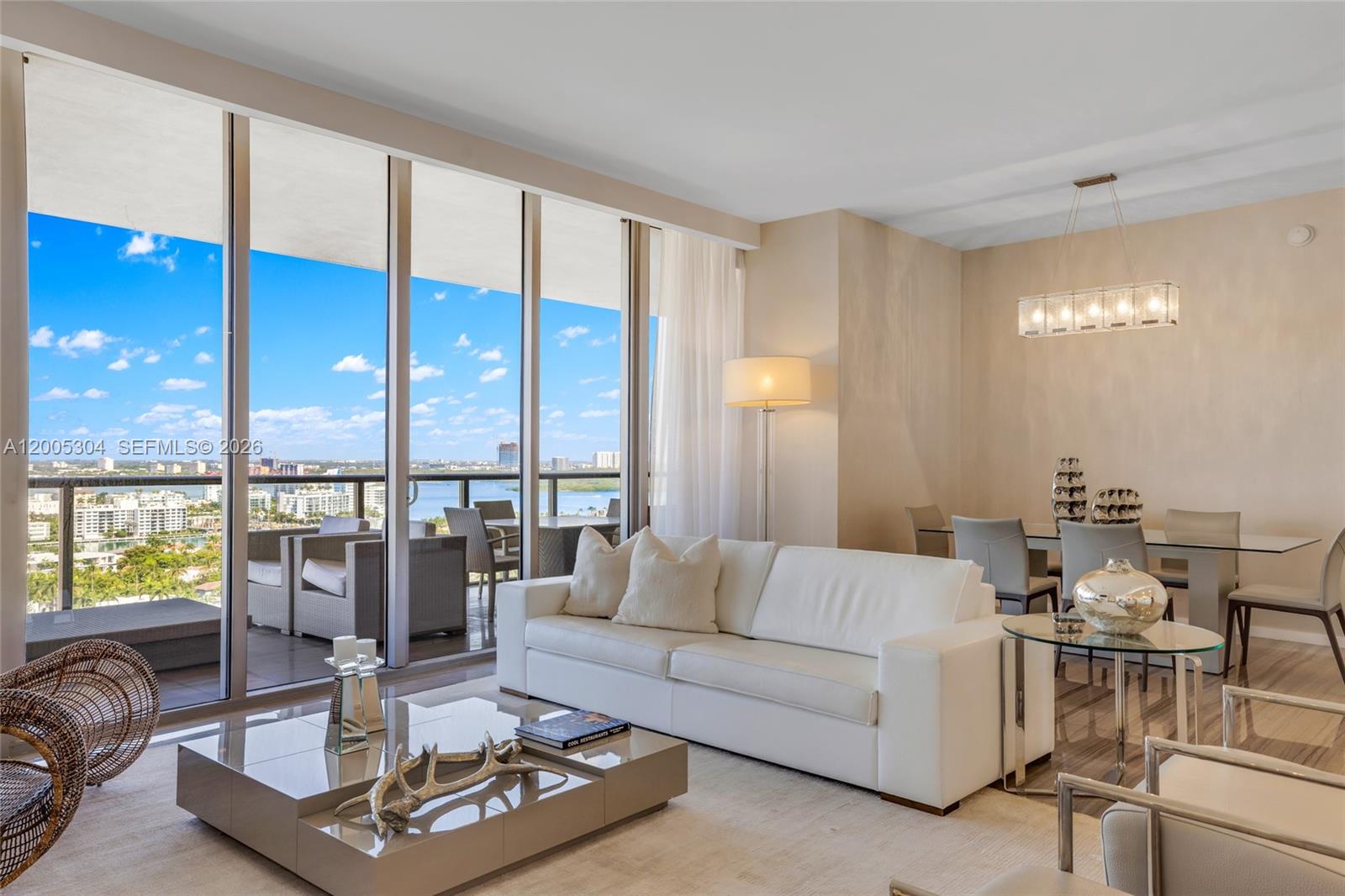 A bright living and dining area features a white sofa, glass tables, and a balcony view — 9705 Collins Ave # 1805N, Bal Harbour FL 33154, BAL HARBOUR, FL