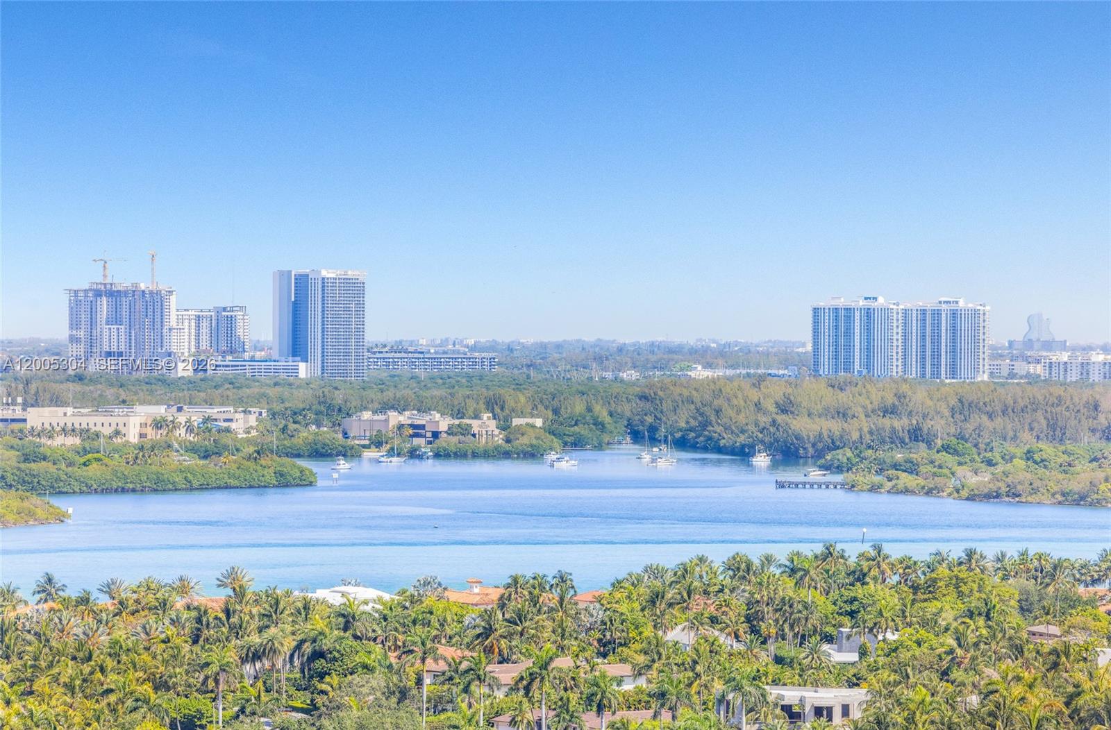 An elevated view of a lake surrounded by dense trees, buildings, and a clear sky — 9705 Collins Ave # 1805N, Bal Harbour FL 33154, BAL HARBOUR, FL
