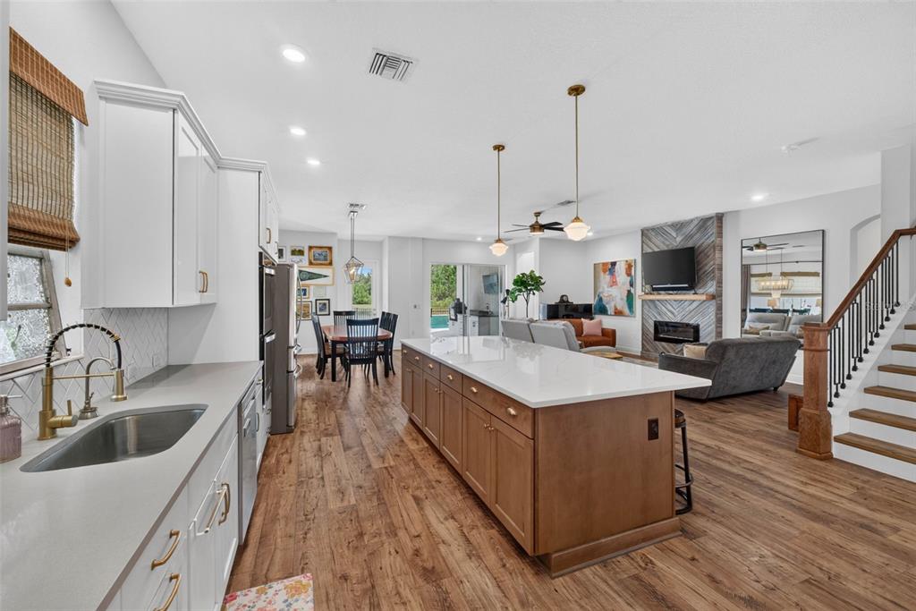 An open-concept kitchen with a wooden island, white cabinets, and a view of the living room — 4282 AMPED WAY, LAND O LAKES, FL