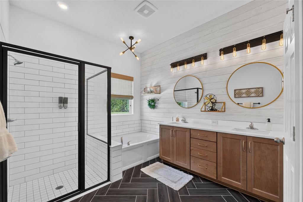 A bathroom features a glass-enclosed shower, a soaking tub, double vanity, and herringbone floor tiles — 4282 AMPED WAY, LAND O LAKES, FL
