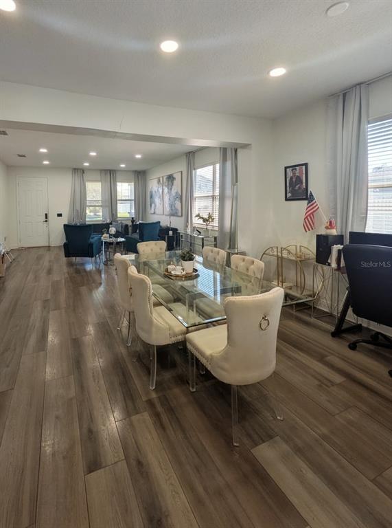 A dining area with a glass table and upholstered chairs sits adjacent to a living room — 2047 BEARING LANE, KISSIMMEE, FL