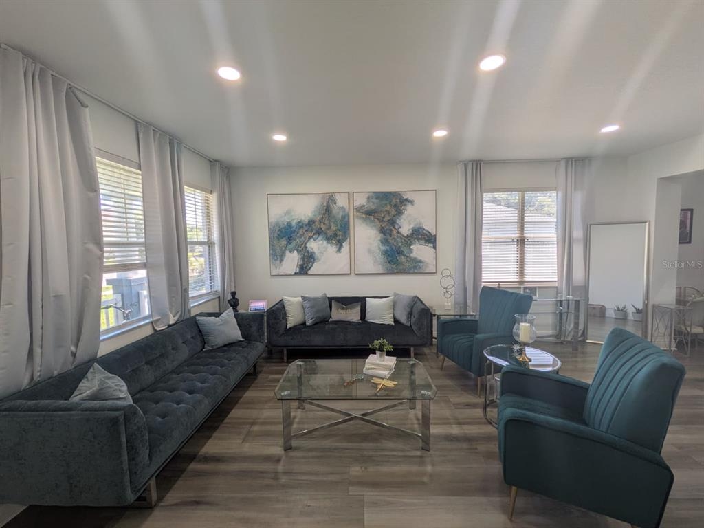 A living room features a blue velvet sofa, matching armchairs, a glass coffee table, and artwork — 2047 BEARING LANE, KISSIMMEE, FL