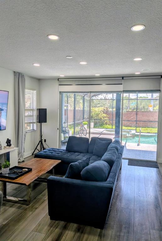 A living room features a blue sectional sofa, wood coffee table, and sliding glass doors — 2047 BEARING LANE, KISSIMMEE, FL