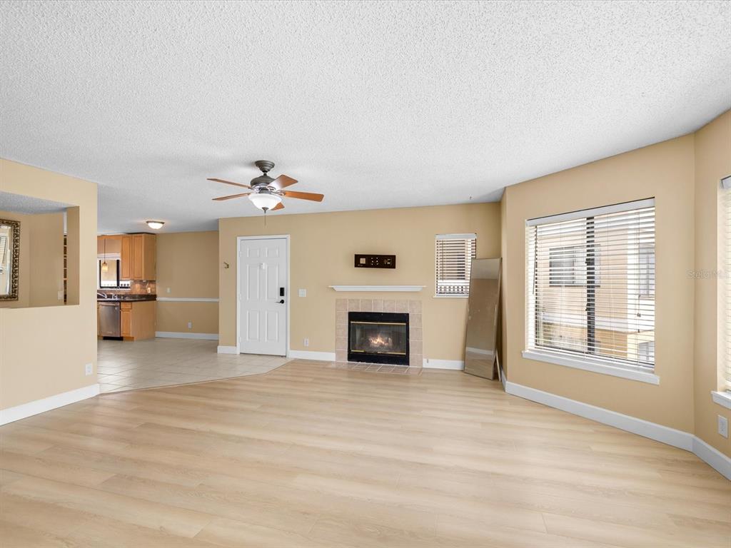 A living room with light wood flooring, a fireplace, and an adjacent kitchen area — 1550 S BELCHER ROAD UNIT 421, CLEARWATER, FL