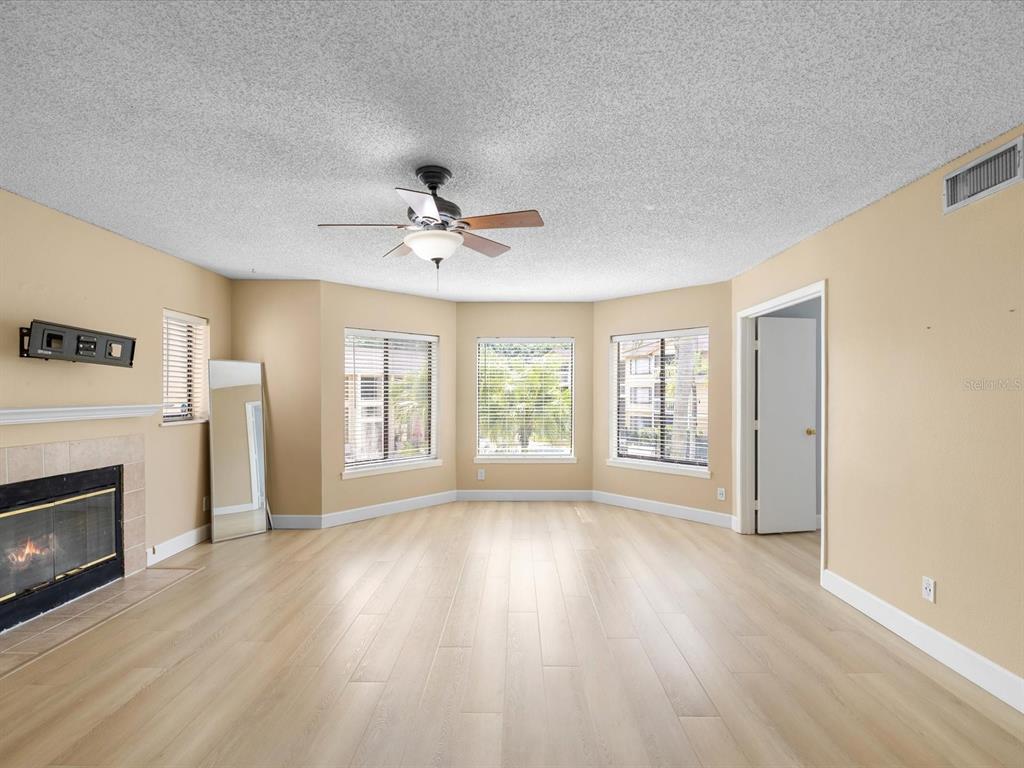 A living room with light wood flooring, a fireplace, and a bay window — 1550 S BELCHER ROAD UNIT 421, CLEARWATER, FL