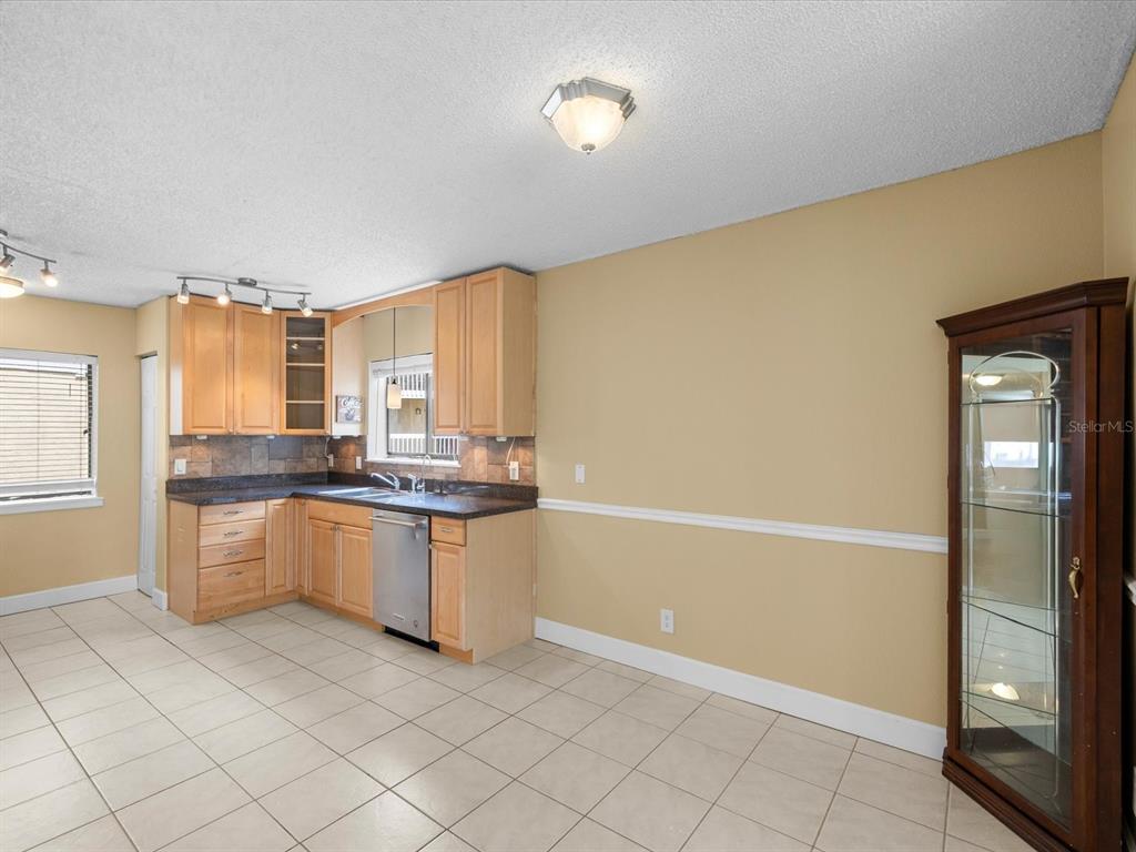 A kitchen with light wood cabinets, dark countertops, tile flooring, and a glass display cabinet — 1550 S BELCHER ROAD UNIT 421, CLEARWATER, FL
