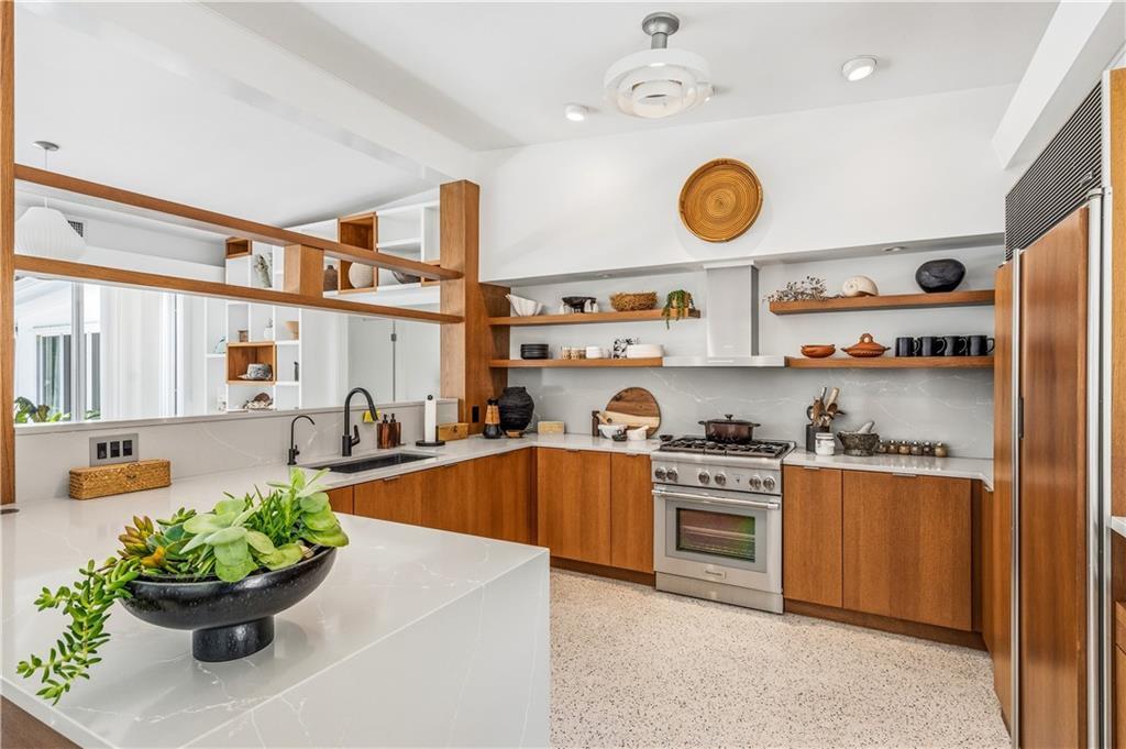 A modern kitchen features wood cabinetry, white quartz countertops, open shelving, and terrazzo flooring — VERO BEACH, FL