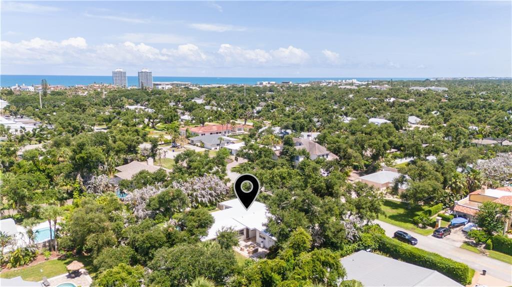 An aerial view shows a residential house with a white roof surrounded by lush trees — VERO BEACH, FL