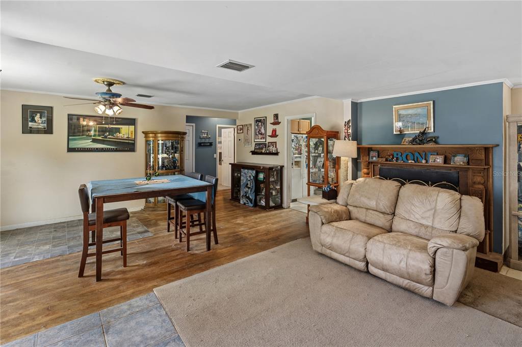 A living and dining area features wood-look flooring, a fireplace, and a ceiling fan — 26015 SACKAMAXON DRIVE, SORRENTO, FL