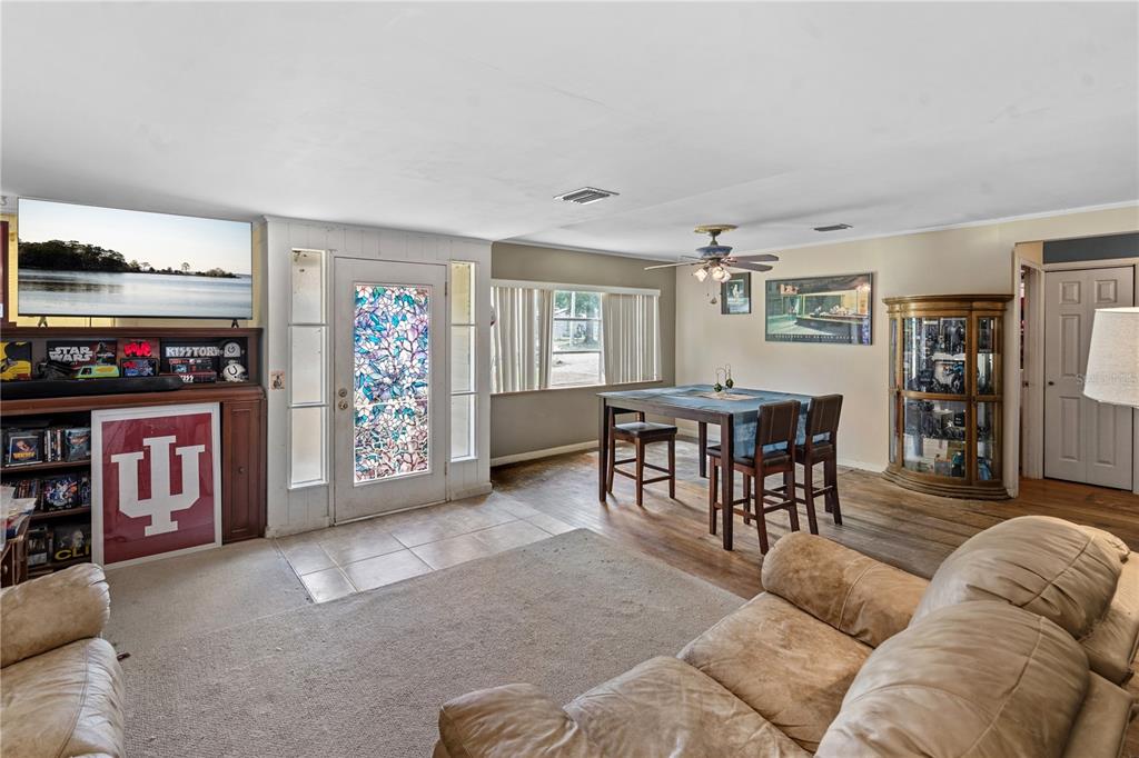 A living and dining area features a stained-glass front door, wood flooring, and a ceiling fan — 26015 SACKAMAXON DRIVE, SORRENTO, FL