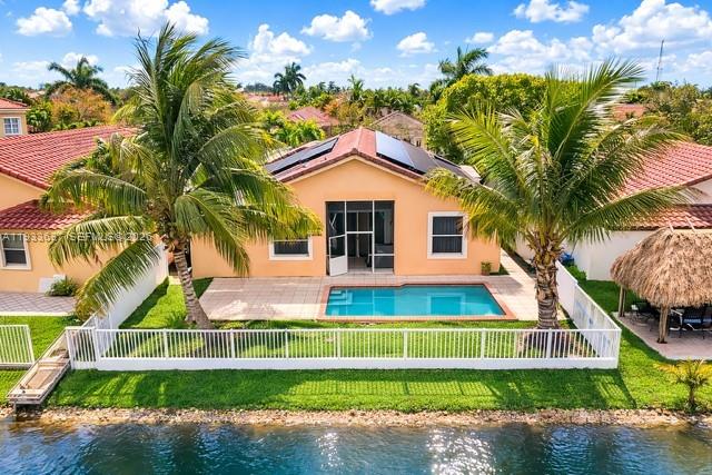 A waterfront house features a swimming pool, a white fence, and palm trees — 13877 SW 50th St, Miramar FL 33027, MIRAMAR, FL