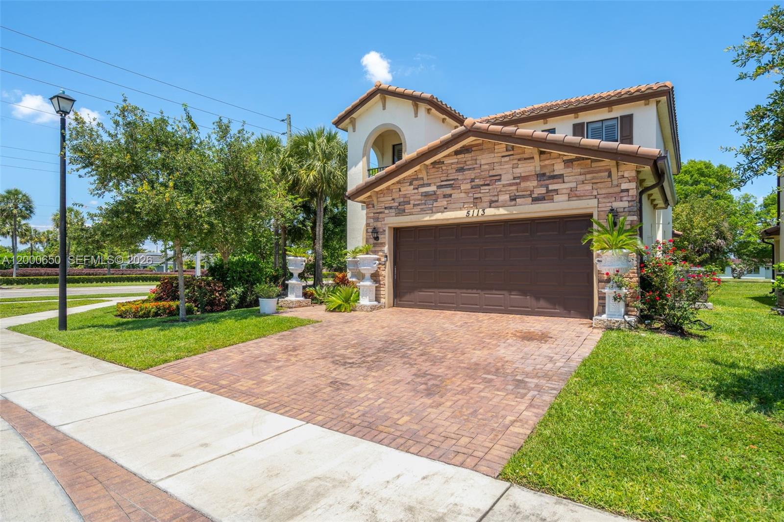 A two-story house with a stone facade, brown garage door, and a brick driveway — 5113 NW 52nd St, Tamarac FL 33319, TAMARAC, FL