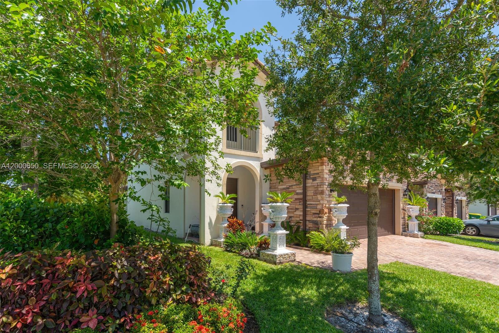 A two-story house with a stone facade, arched entryway, and a paved driveway — 5113 NW 52nd St, Tamarac FL 33319, TAMARAC, FL