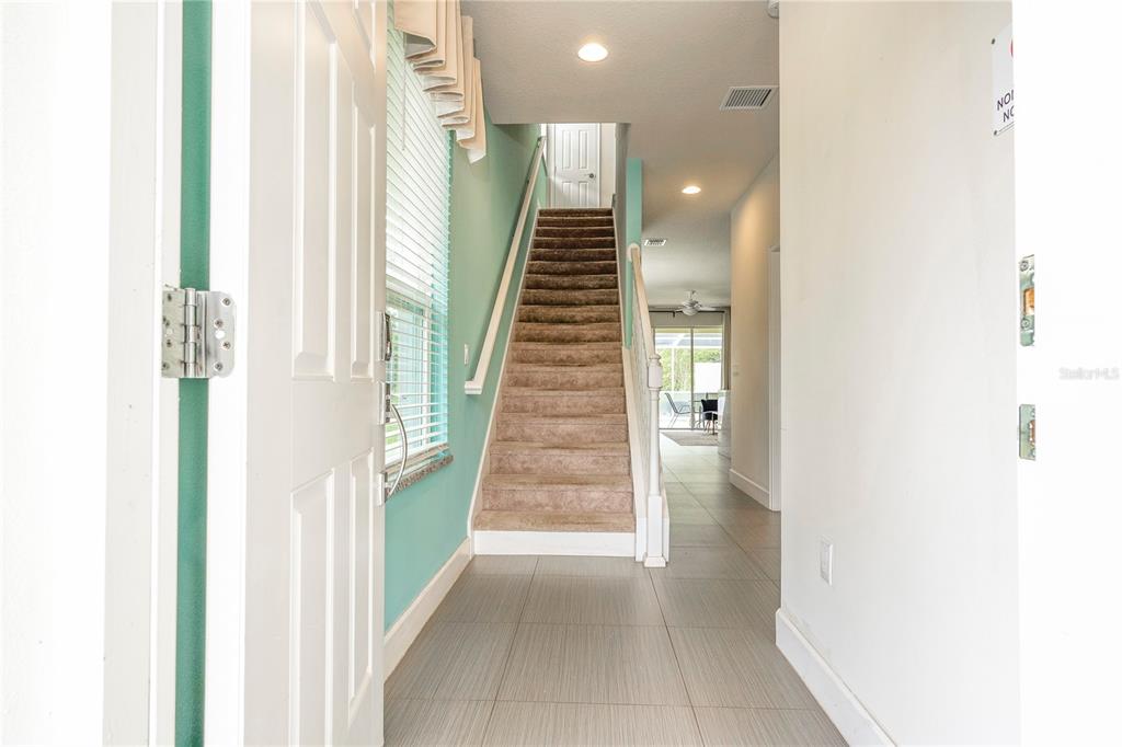 An entryway features a tiled floor, a carpeted staircase, and a view into the home — 1637 TRANQUIL AVENUE, CLERMONT, FL