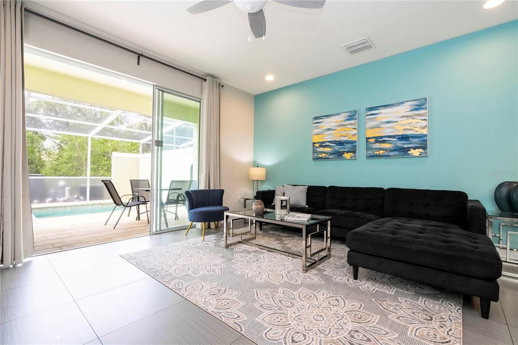 A living room features a black sectional sofa, a patterned rug, and a sliding glass door — 1637 TRANQUIL AVENUE, CLERMONT, FL