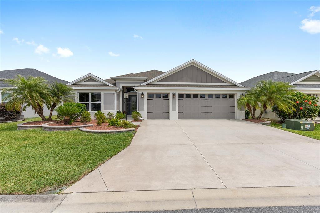 A single-story house with a gray garage, light-colored stucco exterior, and a landscaped front yard — 2140 BILLER CIRCLE, THE VILLAGES, FL