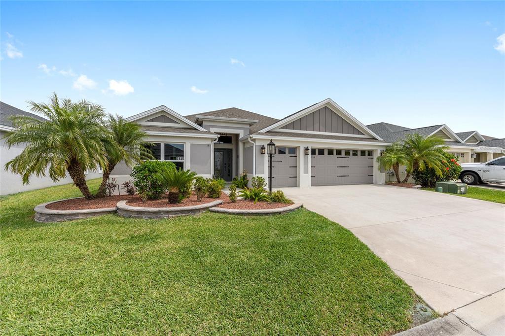 A single-story house with a gray exterior, a two-car garage, and a landscaped front yard — 2140 BILLER CIRCLE, THE VILLAGES, FL