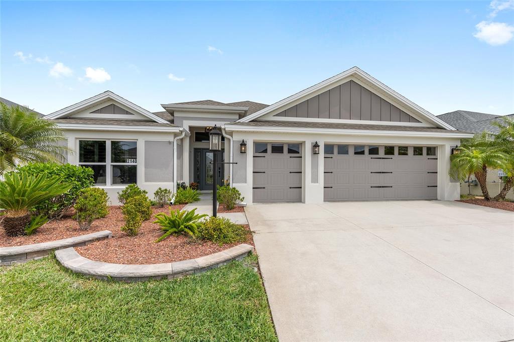 A single-story house with a three-car garage, light stucco exterior, and a landscaped front yard — 2140 BILLER CIRCLE, THE VILLAGES, FL