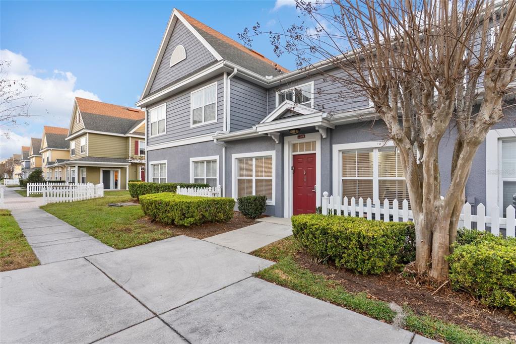 A two-story gray house with a red front door and a white picket fence — 2608 LODI CIRCLE UNIT 104, KISSIMMEE, FL