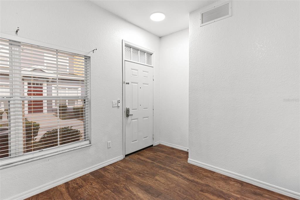 An entryway with wood-look flooring, a white front door, and a window with blinds — 2608 LODI CIRCLE UNIT 104, KISSIMMEE, FL