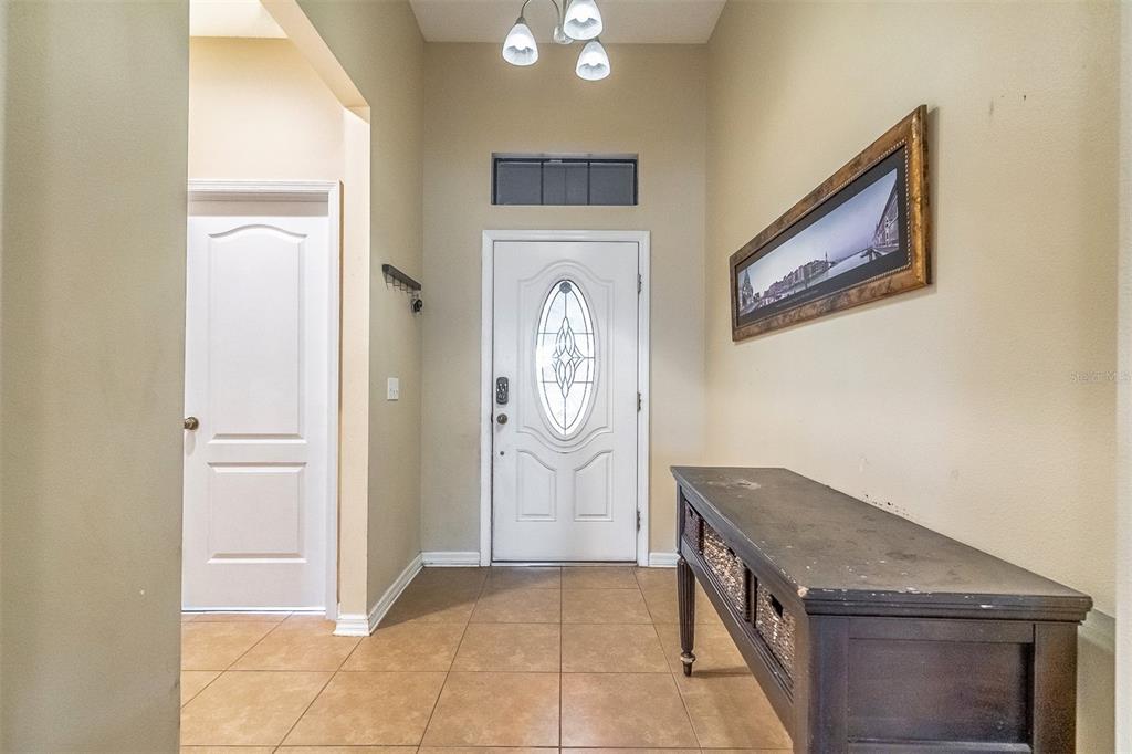 A bedroom features a dark wood bed frame, orange bedding, and a window with blinds — 9907 ARMANDO CIRCLE, ORLANDO, FL