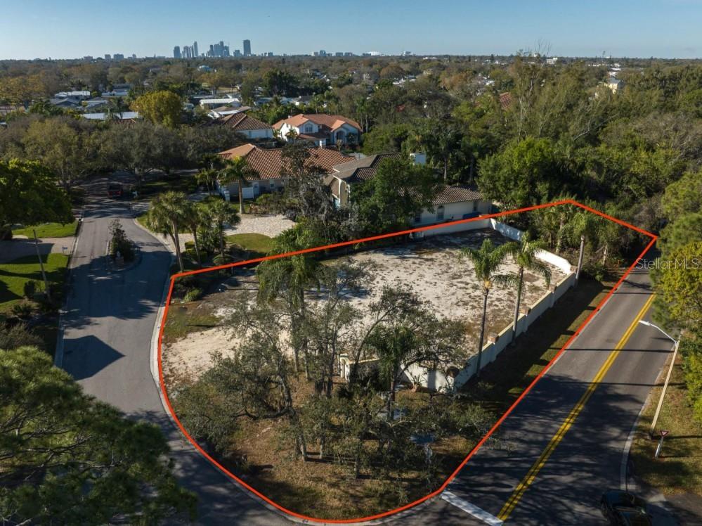 An aerial view shows a vacant, fenced residential lot situated at a street corner — 4690 LAUREL OAK LANE NE, ST PETERSBURG, FL