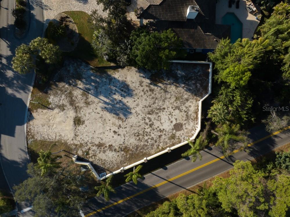 An aerial view shows a vacant, sandy residential lot bordered by a road and trees — 4690 LAUREL OAK LANE NE, ST PETERSBURG, FL
