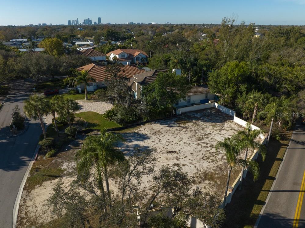 An aerial view shows a vacant, sandy residential lot bordered by a road and trees — 4690 LAUREL OAK LANE NE, ST PETERSBURG, FL
