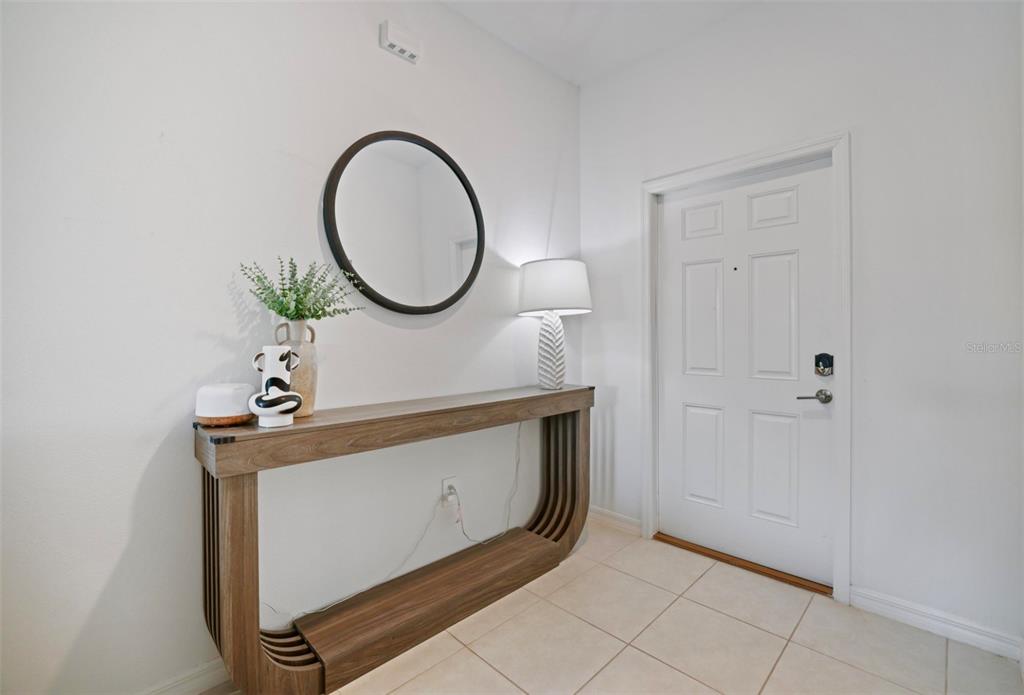 An entryway features a wood console table, a round mirror, and a lamp near a door — 11320 65TH TERRACE E, PALMETTO, FL