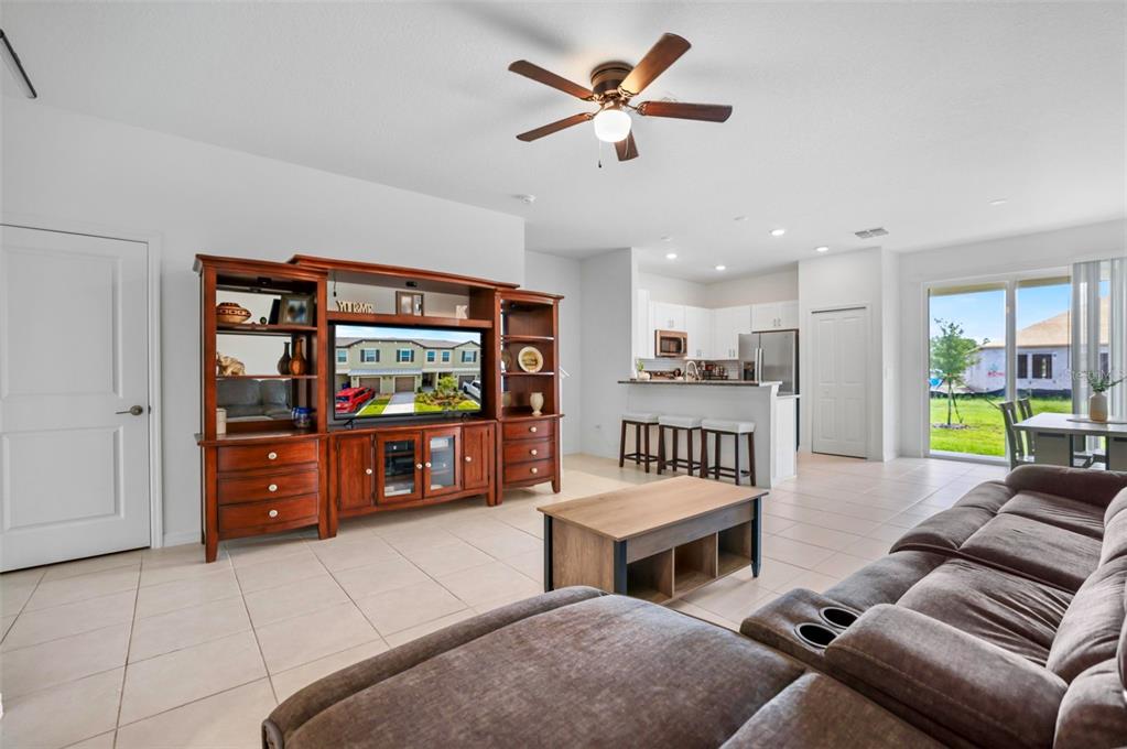 An open-concept living room features a wooden entertainment center, a sectional sofa, and a kitchen — 11320 65TH TERRACE E, PALMETTO, FL