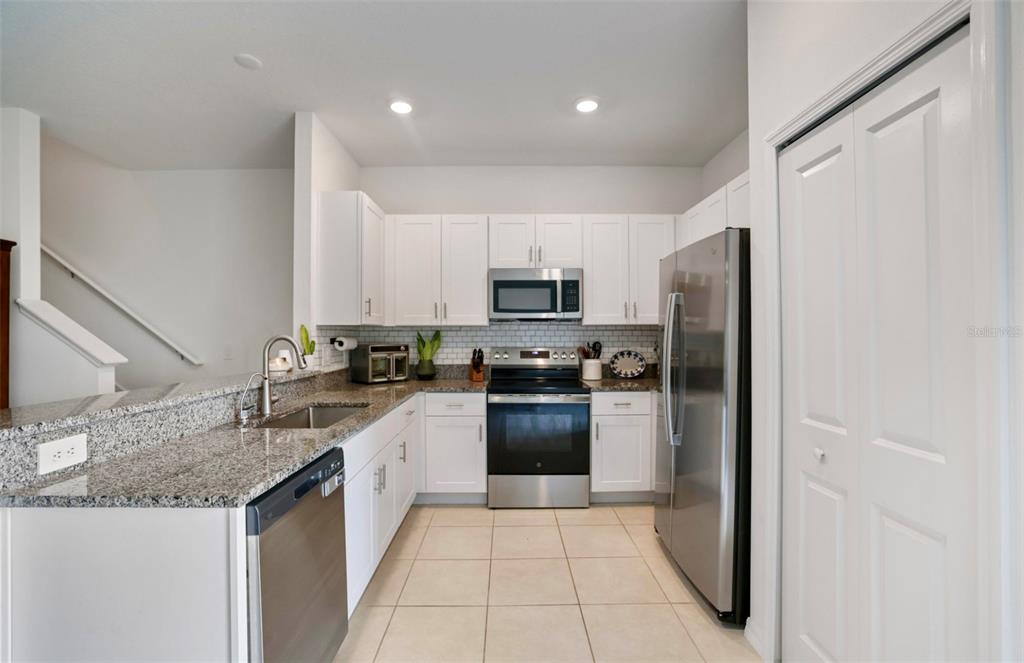 A kitchen features white cabinets, granite countertops, stainless steel appliances, and tile flooring — 11320 65TH TERRACE E, PALMETTO, FL