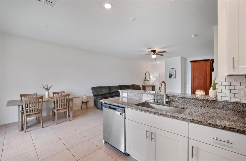 A kitchen with granite countertops and stainless steel appliances overlooks a dining and living area — 11320 65TH TERRACE E, PALMETTO, FL