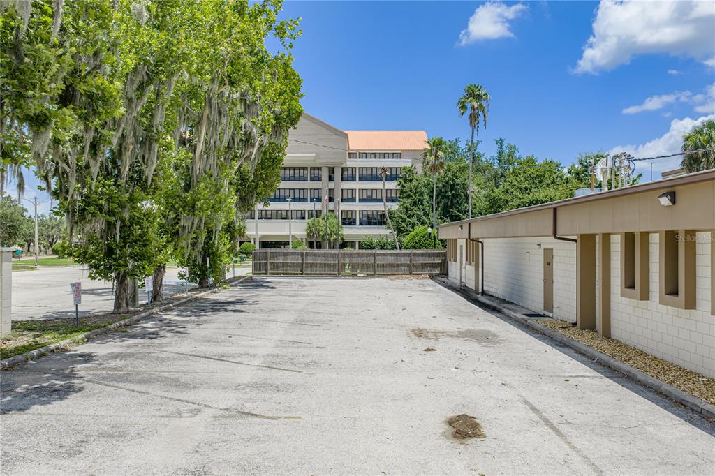 An outdoor parking lot sits beside a low-rise building with a larger office building behind — 215 MARY RECKEWEG WAY, BARTOW, FL