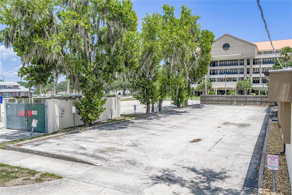 An outdoor paved parking area sits next to a building with trees and a fence — 215 MARY RECKEWEG WAY, BARTOW, FL