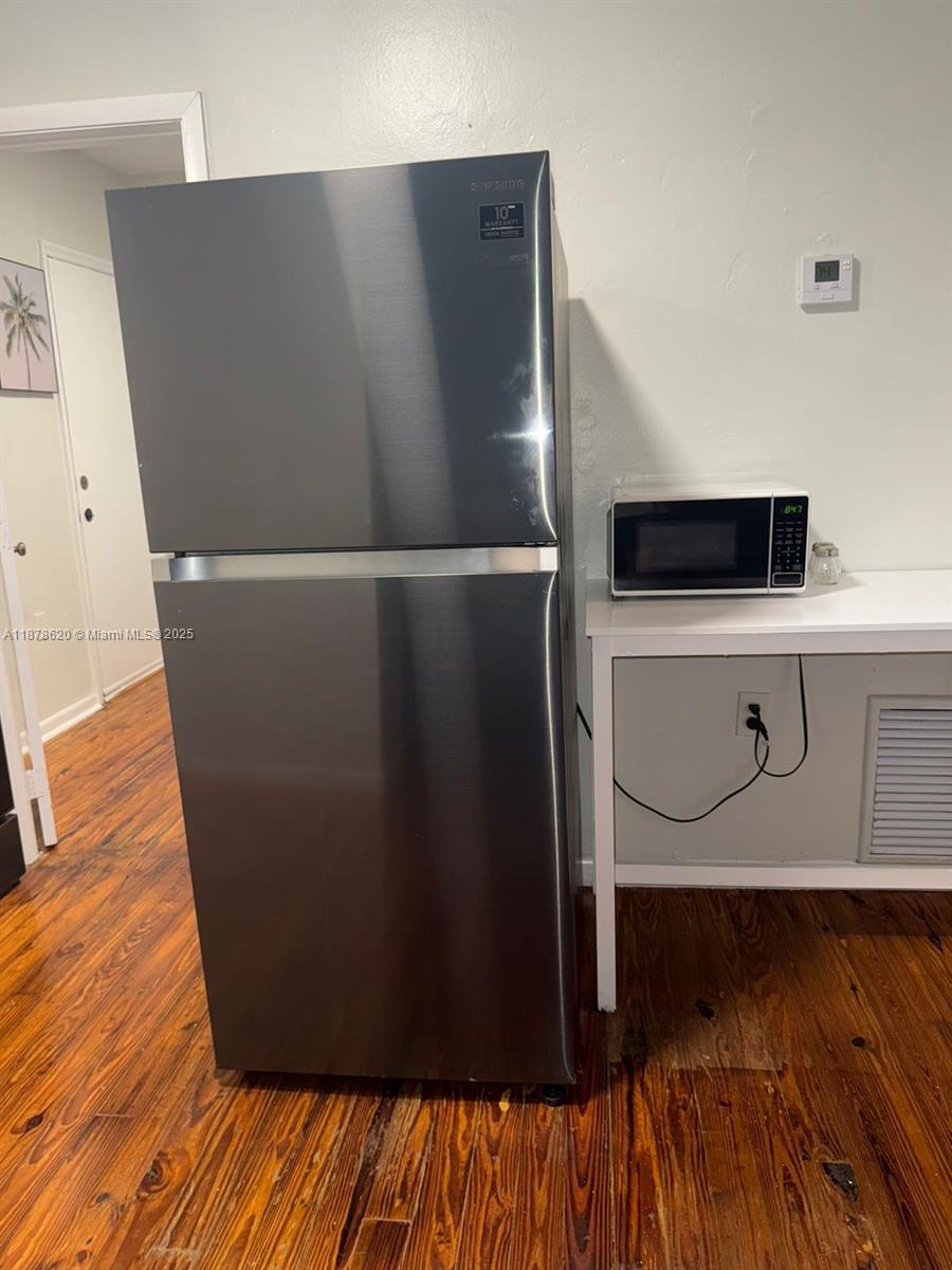 A stainless steel refrigerator stands next to a microwave on a white table — 1289 Marseille Dr # 46, Miami Beach FL 33141, MIAMI BEACH, FL
