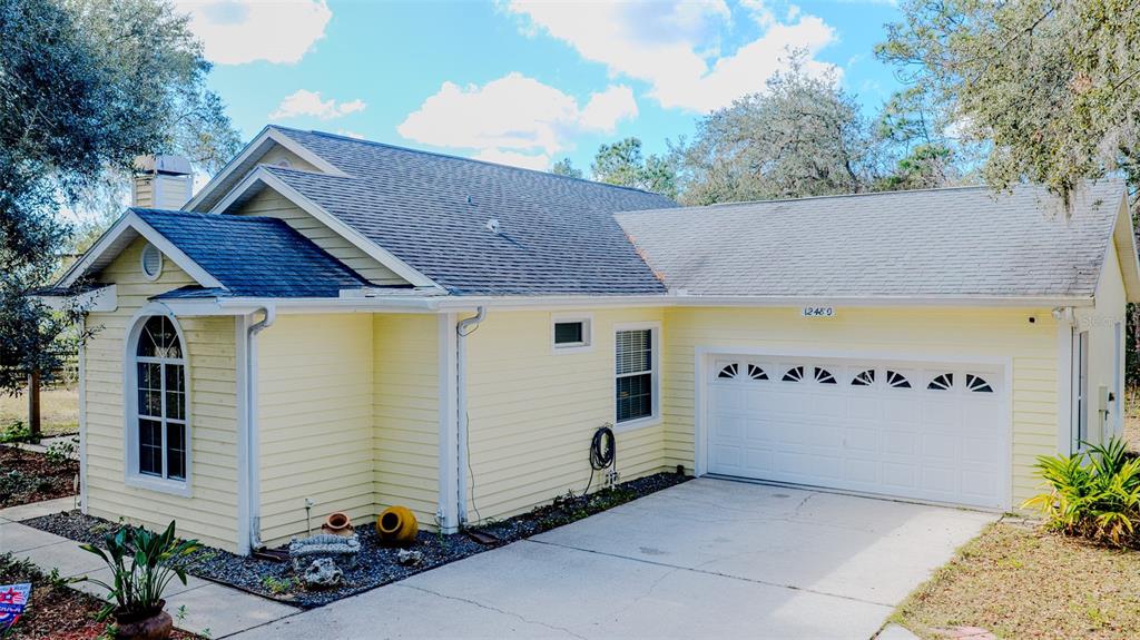 A yellow, single-story house with a two-car garage and a concrete driveway — 12480 S FERN POINT, FLORAL CITY, FL